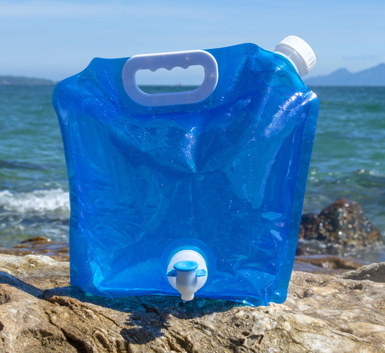 SoraCool Foldable Water Carrier — blue water carrier with tap standing beside the sea